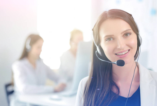 Lächelnde Geschäftsfrau oder Helpline-Betreiberin mit Headset und Computer im Büro - Foto, Bild