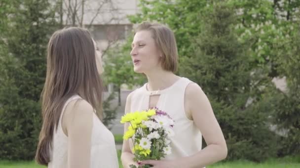 The girl gives flowers. A beautiful daughter gives flowers to her mother - Video