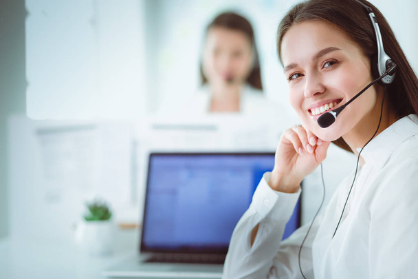 Smiling businesswoman or helpline operator with headset and computer at office - Foto, afbeelding