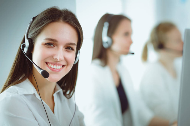 Smiling businesswoman or helpline operator with headset and computer at office - Fotoğraf, Görsel