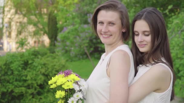 Meeting Daughter and Her Mother in the Park. Attractive Brunette is Hugging Her Mom with Love and Tenderness - Materiał filmowy, wideo