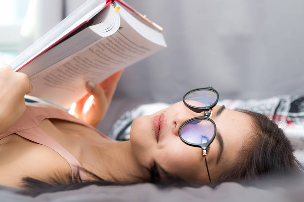 Étudiant asiatique femmes lecture livre sur confortable lit condominium chambre
 - Photo, image