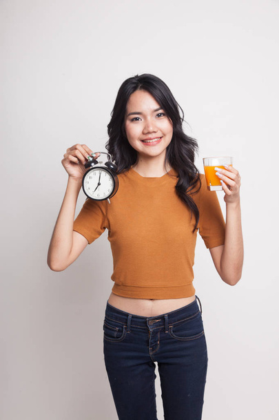 Asian woman with a clock drink orange juice. - Foto, Imagem