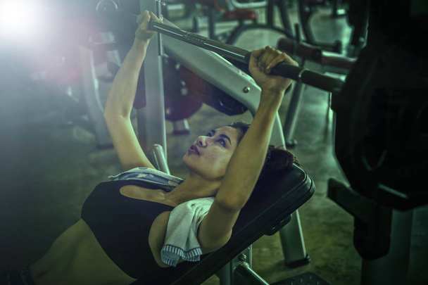 Sports young woman doing exercises with barbell on bench in the fitness gym. Bar Bench Press. - Fotoğraf, Görsel