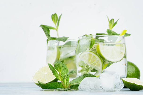 Mojito in two glasses with mint, slices lime, ice cubes, straw on soft white background, copy space. - Φωτογραφία, εικόνα