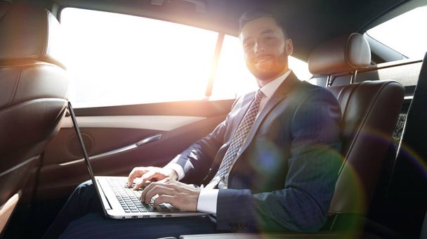 young businesswoman working on her laptop while sitting in the car - Foto, Bild