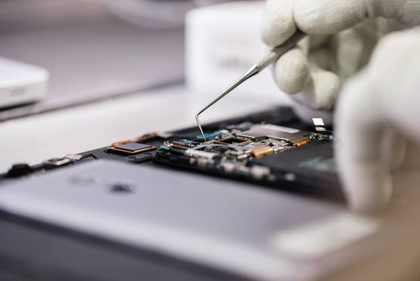 Work with a microscope. Microelectronics device. Close-up hands of a service worker repairing modern smartphone. Repair and service concept. - Foto, Bild