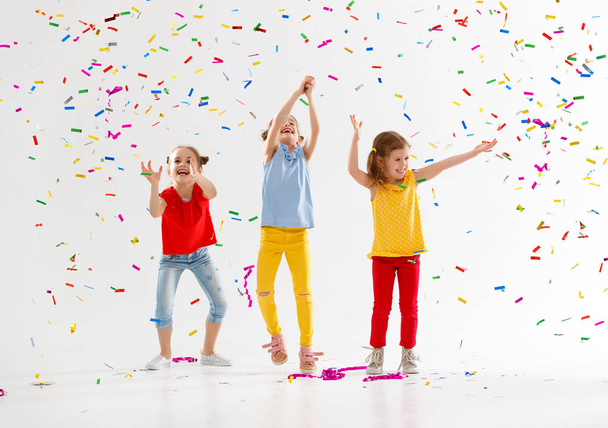 fröhliche Kinder im Urlaub springen in buntem Konfetti auf  - Foto, Bild