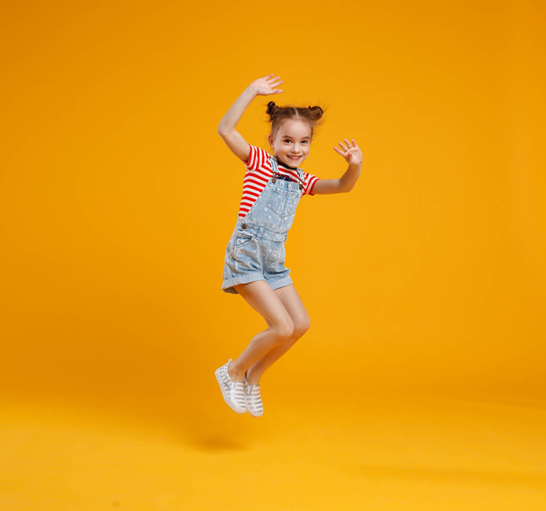 funny child girl jumping on colored yellow background - Photo, Image