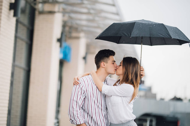 Szczęśliwa Młoda para Ogarnięcie i pocałunek pod parasol w deszczu dzień. Para w miłości relacje koncepcją. - Zdjęcie, obraz