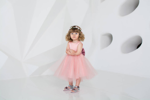 little girl in pink dress smiles in white room - Zdjęcie, obraz