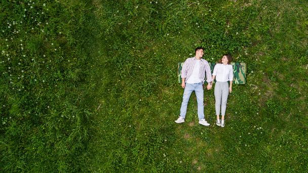 Beautiful in love young couple lying on the grass, view from above - Fotó, kép