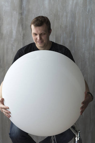 A man holding an inflatable ball on a gray background. - Foto, Imagen