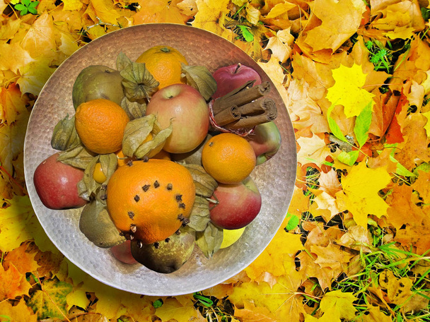 Fruit platter with spiced fruits on yellow red and green autumn leaves, seasonal background and copy space. - Photo, Image