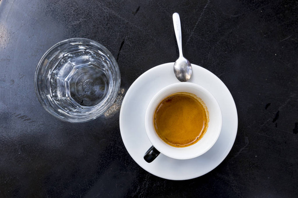 espresso coffee with foam in white cup on black table - Fotoğraf, Görsel