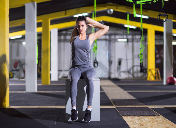 young athletic woman warming up and stretching on fit box at crossfitness gym - Fotografie, Obrázek