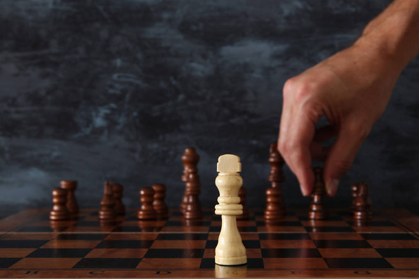 Bild eines Geschäftsmannes, der eine Schachfigur über ein Schachbrett bewegt. Business, Wettbewerb, Strategie, Führung und Erfolgskonzept. - Foto, Bild
