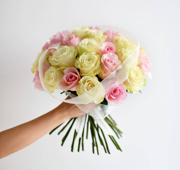 Beautiful woman hand hold bouquet of yellow and pink roses  flowers on white - Φωτογραφία, εικόνα