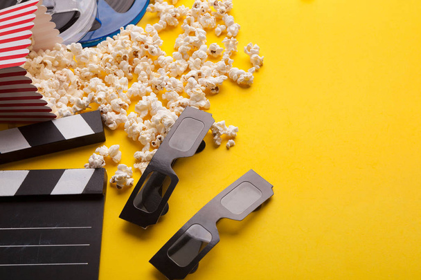 Clapperboard, 3D glasses and popcorn on yellow background - Фото, изображение