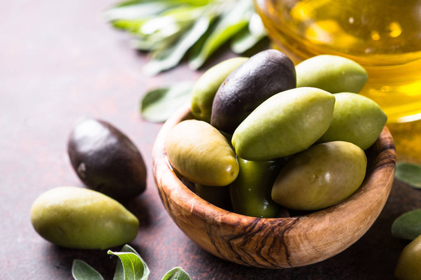 Olives and olive oil on dark stone table. - Foto, Bild