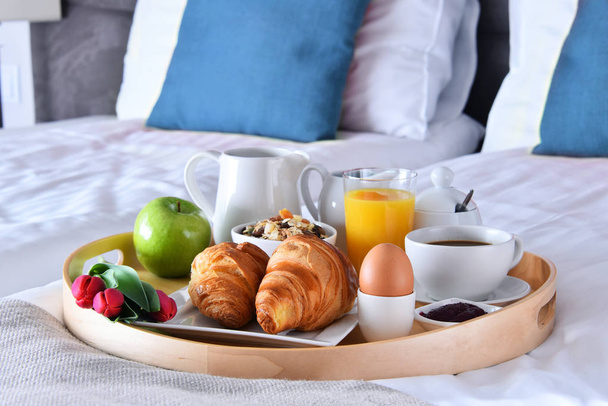 Ontbijt op dienblad op bed in hotelkamer - Foto, afbeelding
