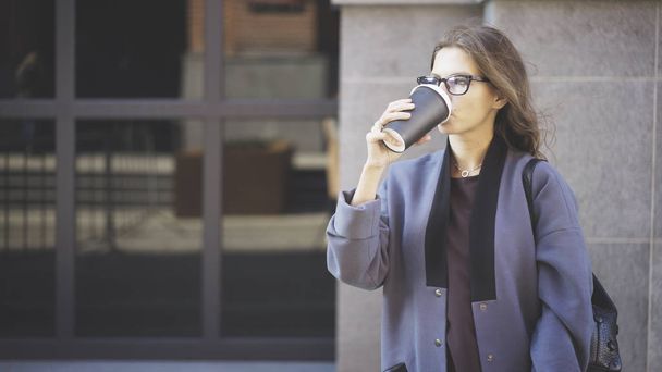 Businesswoman in glasses drinking coffee outside - Fotografie, Obrázek