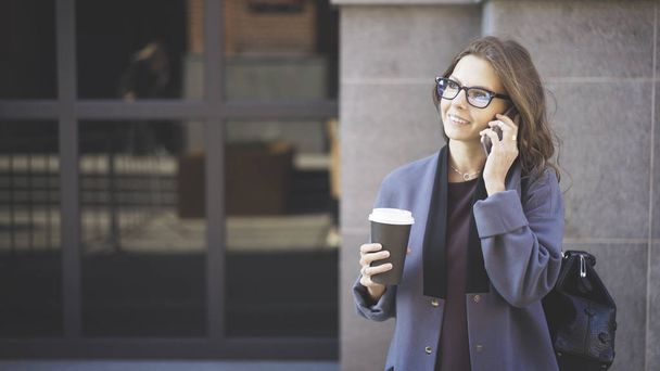 Cheerful woman on the phone with coffee outside - Photo, image