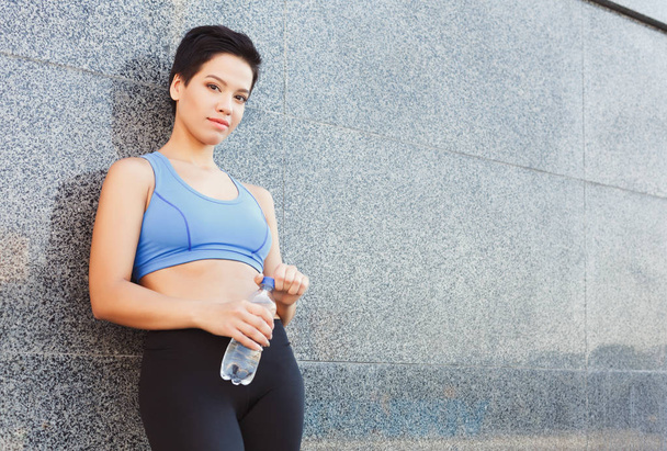 Vrouw runner heeft pauze, drinkwater - Foto, afbeelding