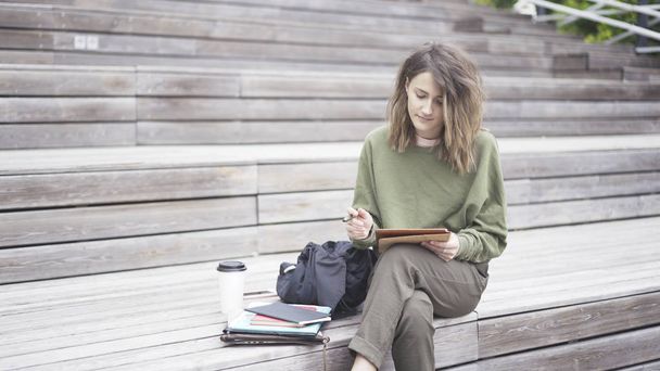 Una ragazza è seduta sulle scale a lavorare con un tablet
 - Foto, immagini