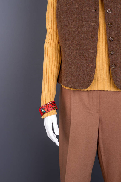 Etalagepop met bruin vest en rode armband. - Foto, afbeelding