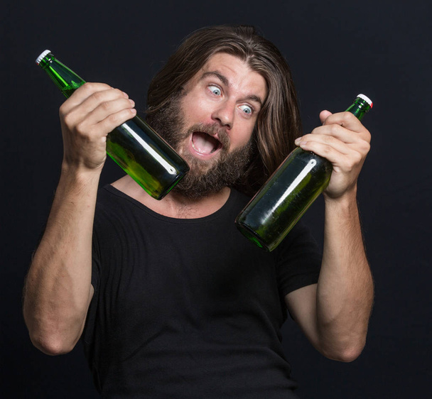 Bearded Man hipster holds bottle of beer isolated on black - Photo, image