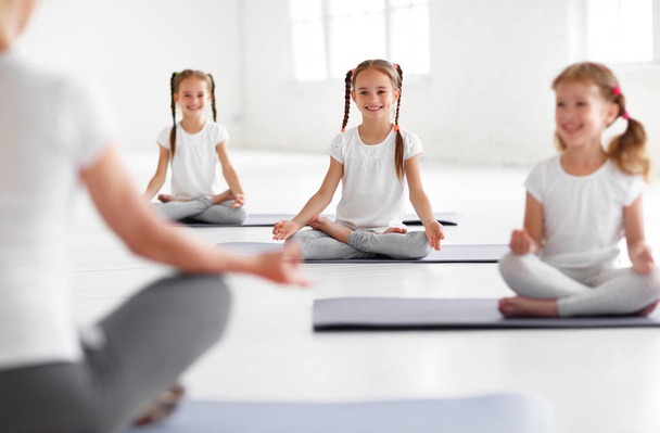 Kinder üben Yoga in Lotus-Pose mit Lehrerin - Foto, Bild