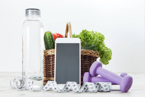 Κινητό τηλέφωνο με καλάθι λαχανικών και συσκευές γυμναστικής - Φωτογραφία, εικόνα