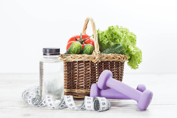 Cesta con verduras y mancuerna, cinta métrica, botella de agua
 - Foto, imagen