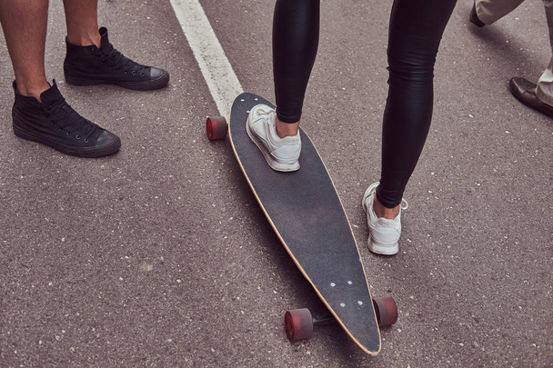 Conceito de lazer e esportes - close-up de pés de casal adolescente com um longboard em uma rua
. - Foto, Imagem