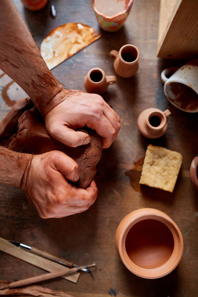 Potier mâle moulant une argile dans un atelier de poterie, gros plan, mise au point sélective, vue de dessus
. - Photo, image