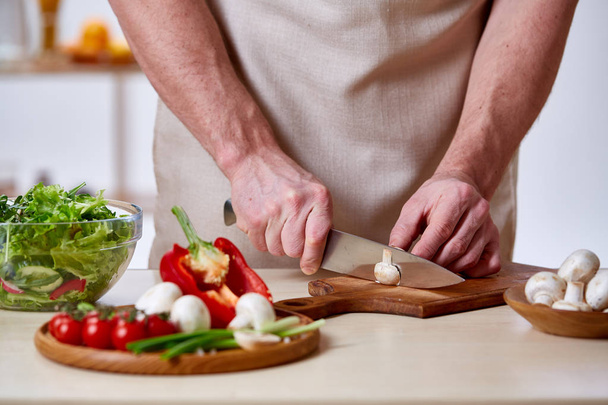 Man cooking at kitchen making healthy vegetable salad, close-up, selective focus. - Photo, image