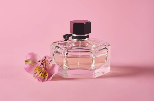 Bottle with perfume and fresh pink flower on pink background. Minimal concept - Φωτογραφία, εικόνα