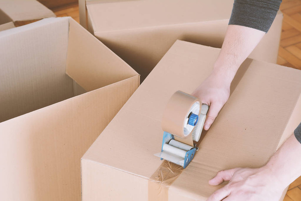 Man sealing a shipping cardboard box - Foto, imagen