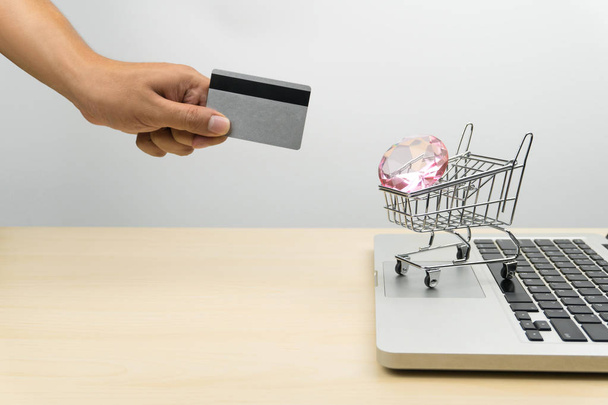 tarjeta de crédito de mano, un diamante en un carrito de compras en un ordenador portátil, concepto de compras en línea
 - Foto, Imagen