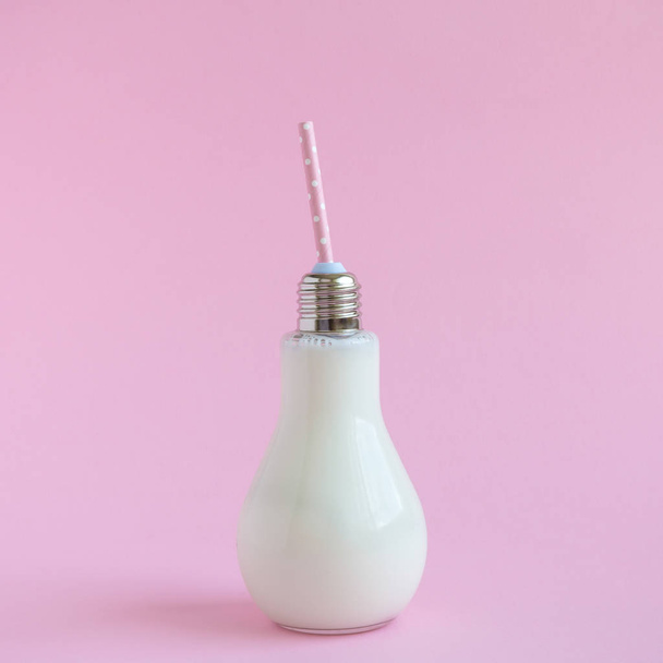 Glass bulb bottle of milk on rose background. - Zdjęcie, obraz