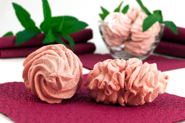 Dois marshmallows rosa em um guardanapo de bardo com ramos de hortelã verde
. - Foto, Imagem