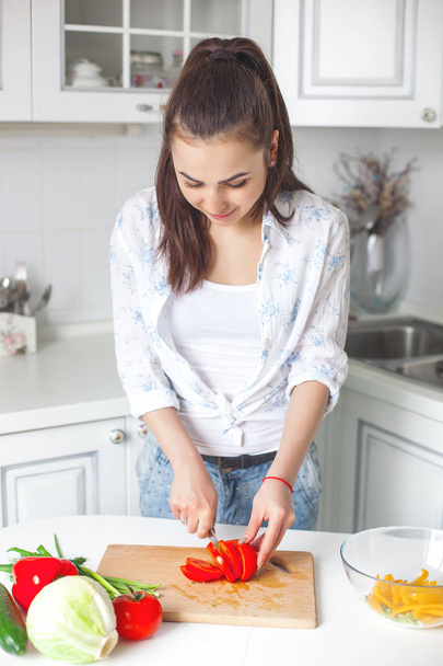 Jeune femme attrayante cuisine salade à l'intérieur à la cuisine
 - Photo, image