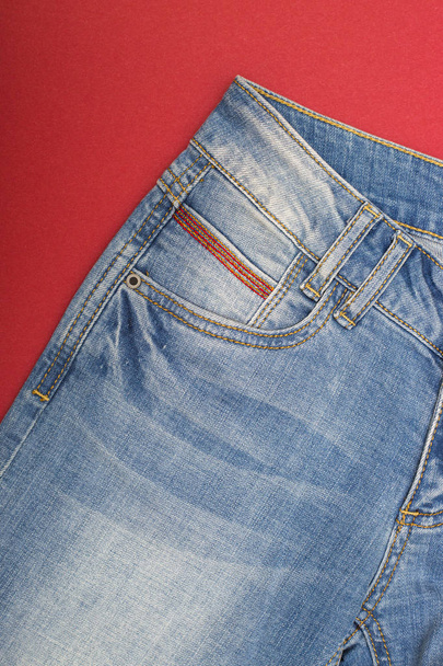 Fragment otrhaný džíny světle modré na červeném pozadí - Fotografie, Obrázek