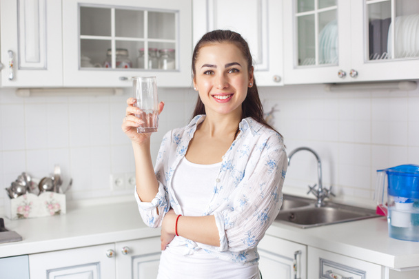 Νεαρή γυναίκα υγιεινό πόσιμο φιλτραρισμένο νερό στην κουζίνα - Φωτογραφία, εικόνα