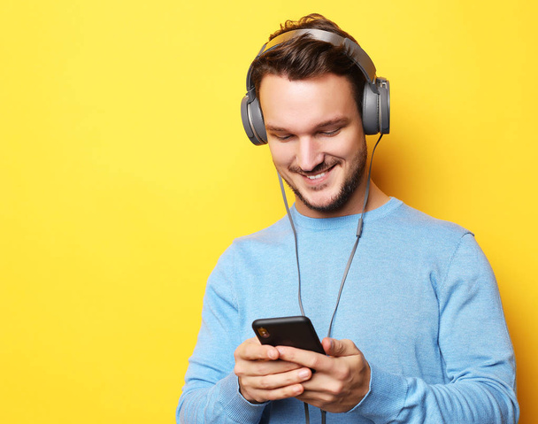 young man wearing headphones and holding mobile phone - Foto, immagini