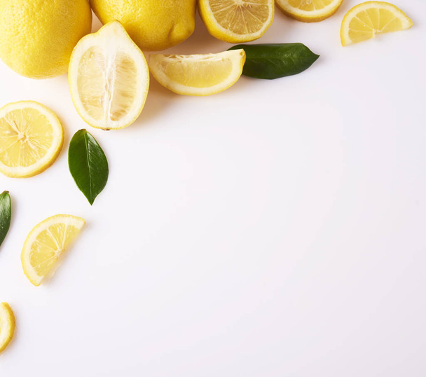 Stapel van verse gele citroenen en groene bladeren geïsoleerd op witte achtergrond - Foto, afbeelding