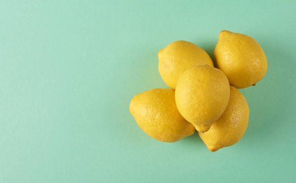Fresh yellow lemons on turquoise background with space for your text - Photo, Image