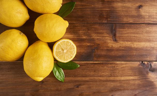 Fresh yellow lemons on brown wooden background with space for your text - Zdjęcie, obraz