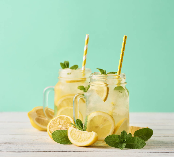 frische leckere Limonade in Einmachgläsern auf Holztisch vor türkisfarbenem Hintergrund - Foto, Bild